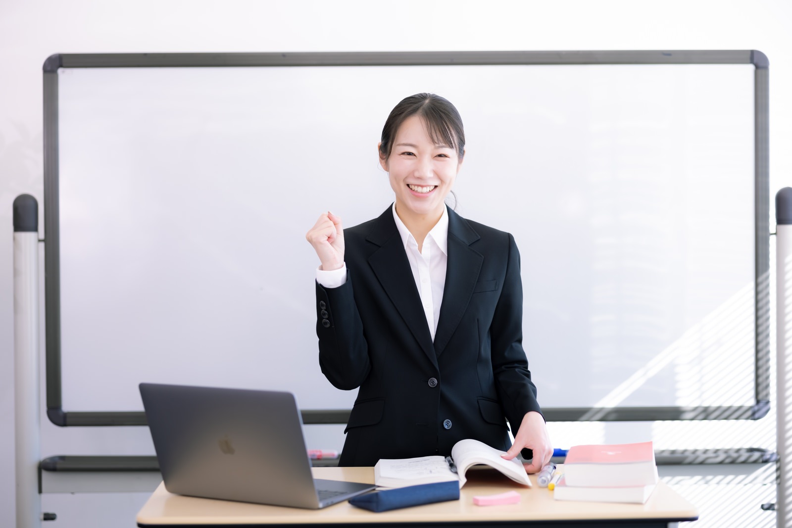 スーツ姿で資格勉強を頑張る笑顔の女性社会人