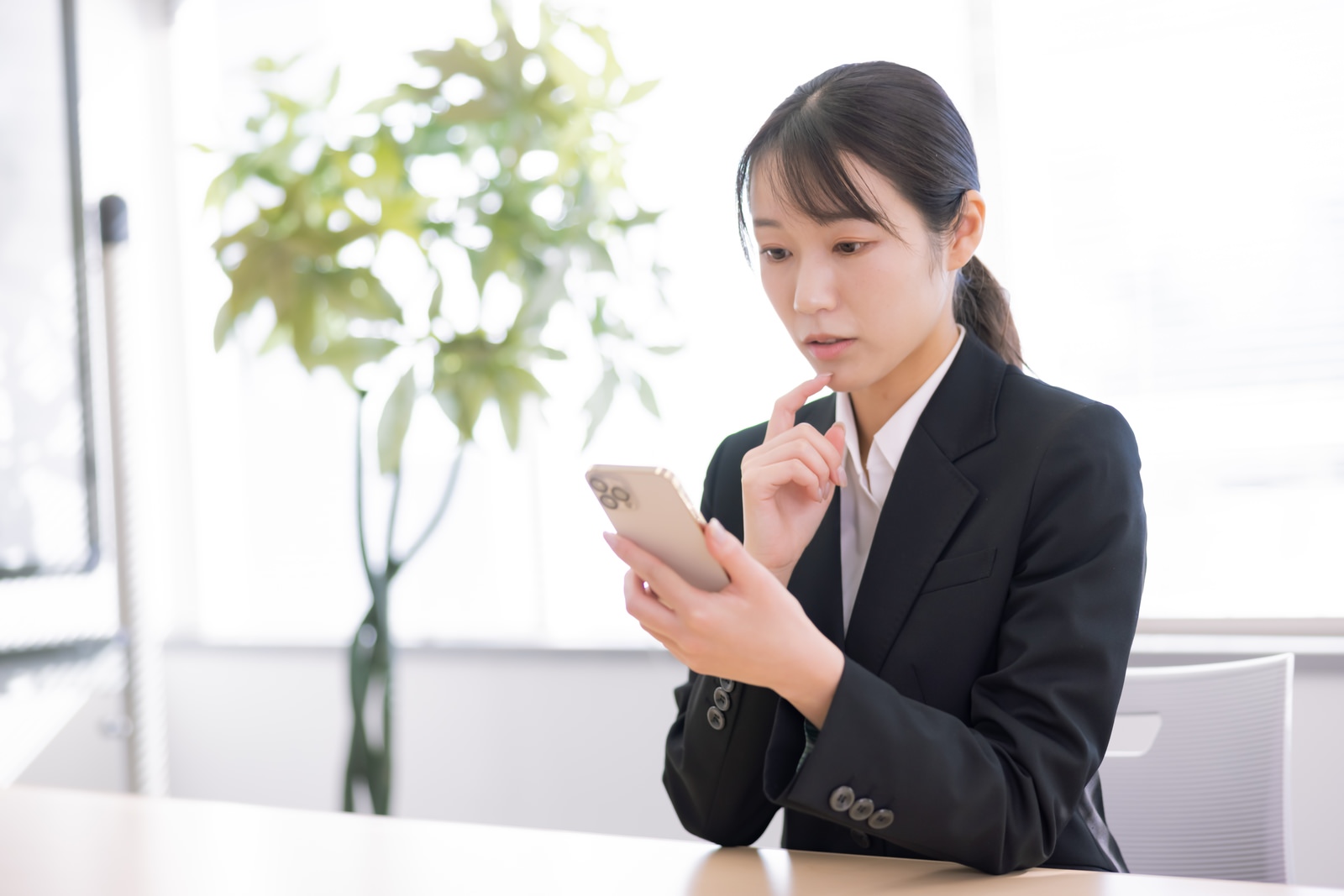 スーツ姿の女性がスマートフォンを見ながら学習している様子