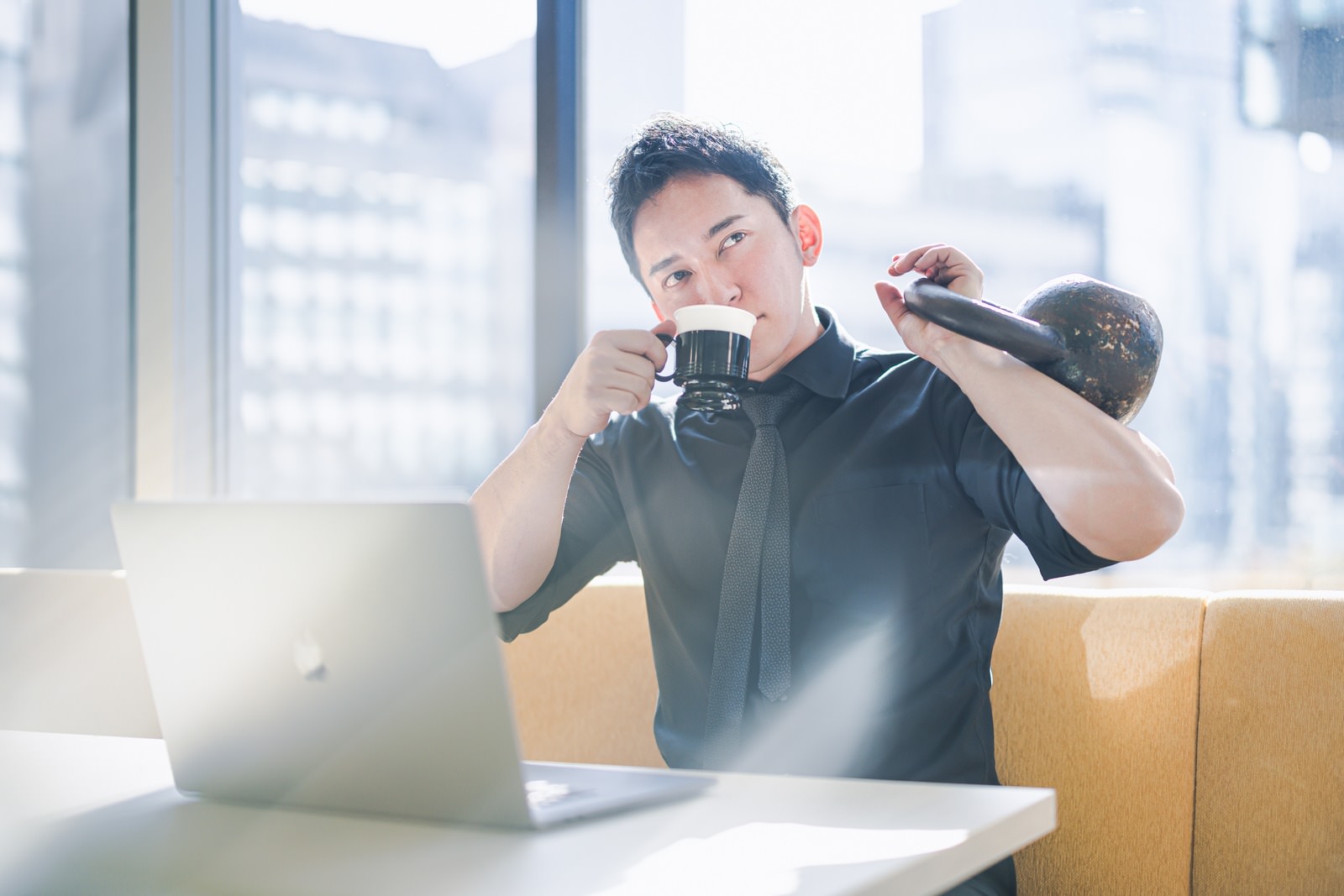 パソコン作業しながらコーヒーとケトルベルでトレーニングする男性｜FP3級の暗記を効率化するイメージ